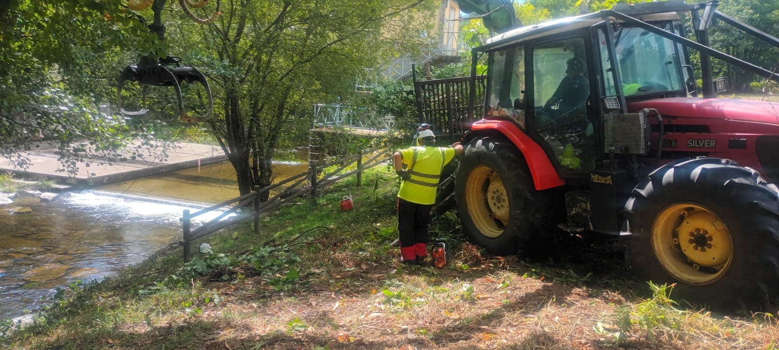 Tractor forestal y operario trabajando junto a un cauce de agua